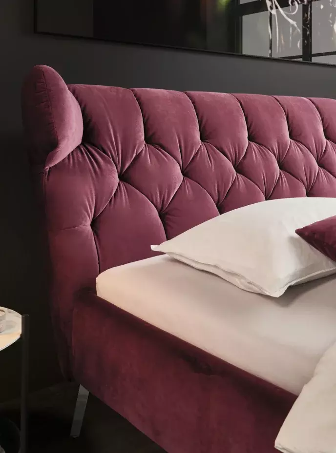 Luxuriöses burgunderrotes Samtbett mit tuftiertem Flügelkopfteil, weißen Bettwäsche, roten Kissen