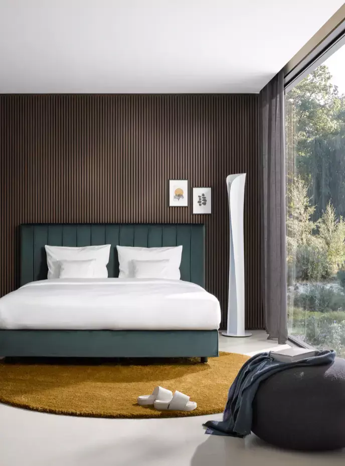 Modernes Schlafzimmer mit türkisem Bett, Holzwand, gelbem Teppich.